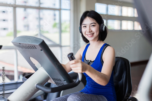 beautiful Asian fitness teenager on bicycle machine doing spinning at fitness.  sport and Healthy concept. Workout with happiness and Cardio ideas. © whyframeshot