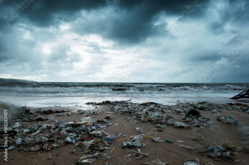 Garbage on beach, environmental pollution in Bali Indonesia. Storm is coming on background. And drops of water are on camera lens. Dramatic view