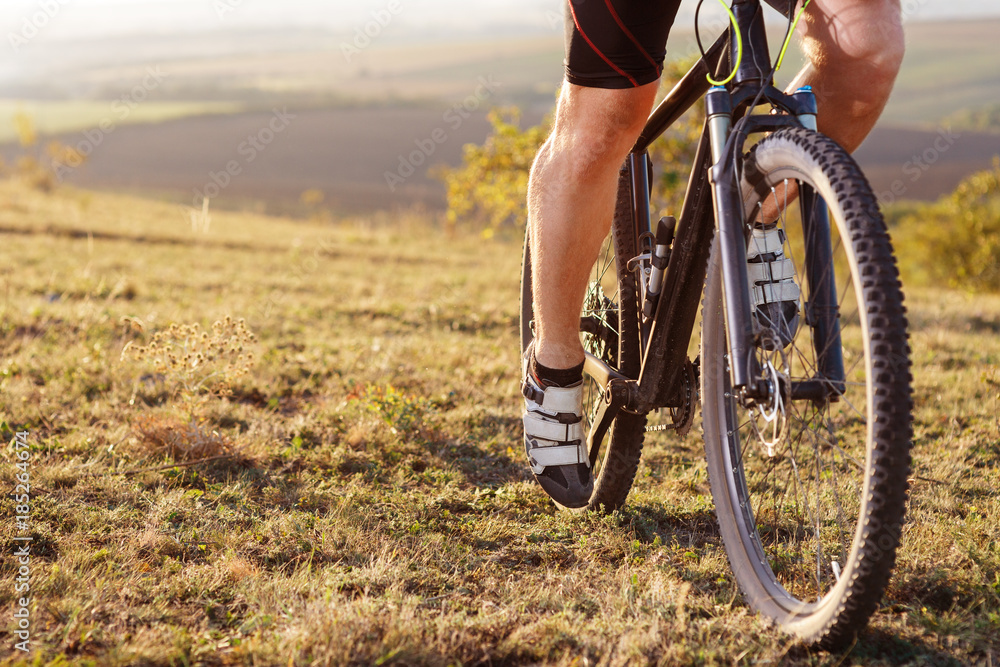 back view of a man with a bicycle and red backpack against the blue sky. cyclist rides a bicycle. back view of a man with a bicycle and red backpack against the blue sky. cyclist rides a bicycle.