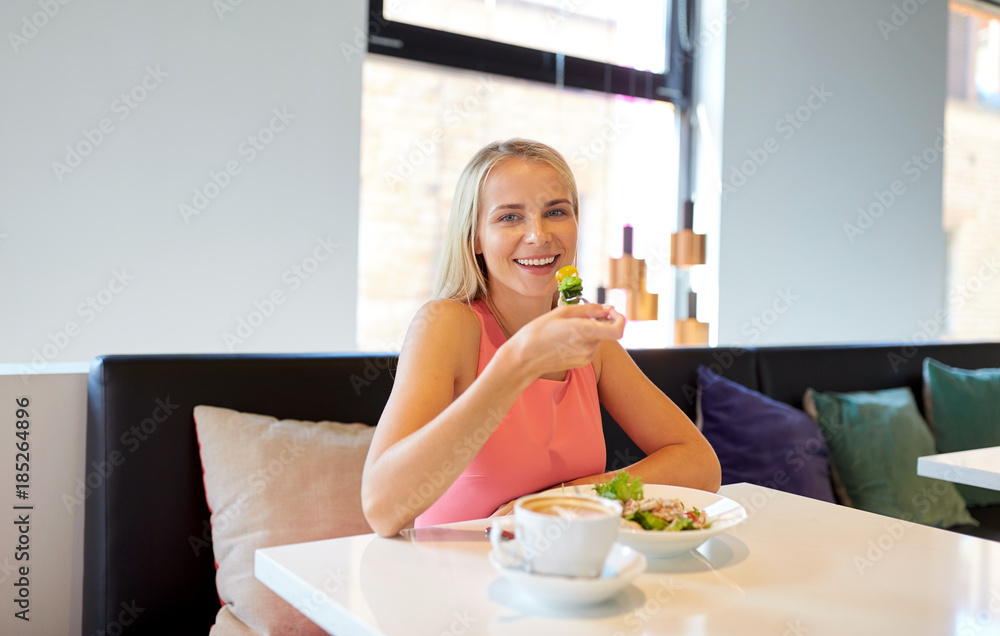 happy young woman eating lunch at restaurant