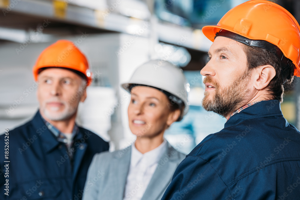 male workers and female inspector in helmets in storehouse male workers and female inspector in helmets in storehouse