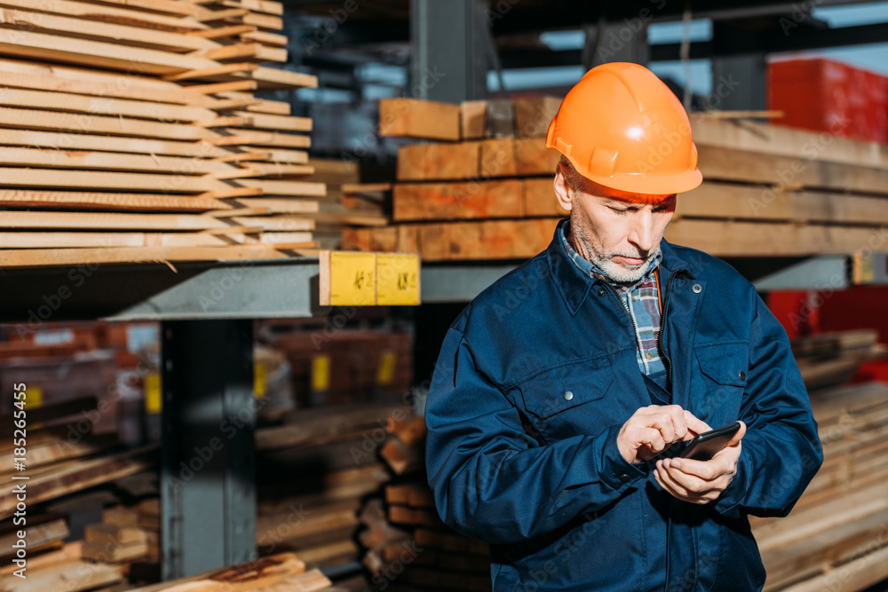 senior builder in helmet using smartphone outside on construction senior builder in helmet using smartphone outside on construction