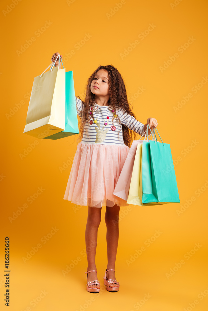 Thinking girl child holding shopping bags. Thinking girl child holding shopping bags.