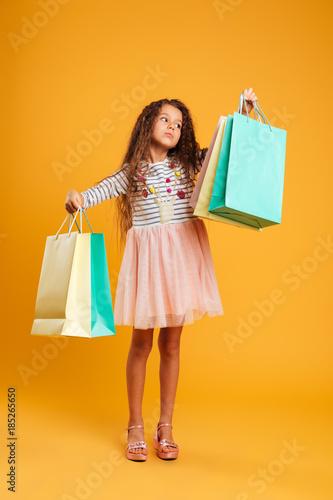 Thinking girl child holding shopping bags.