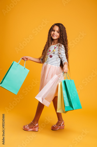 Cheerful girl child holding shopping bags.