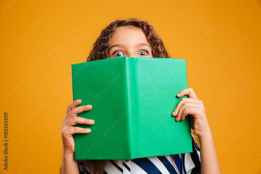 Excited shocked little girl child covering face with book. Excited shocked little girl child covering face with book.