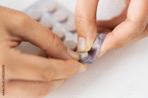 woman hands opening pack of medicine pills