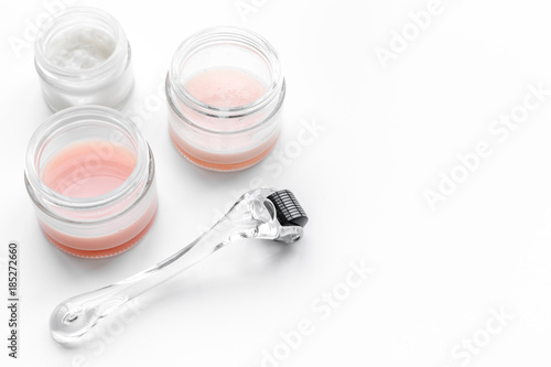 Cosmetoligist's instruments. Dermaroller and cosmetics mask and cream on white background copyspace