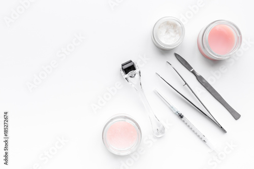 Dermatologist or cosmetologist accessories. Dermaroller, creams and mask, beauty injection, tools on white background top view copyspace