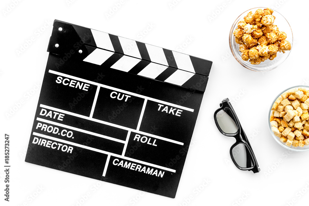 Fast food for watching film. Popcorn, rusks near glasses and clapperboard on white background top view