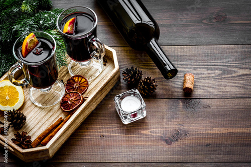 Warm mulled wine with citrus and spices for winter evening near spruce branch on dark wooden background copyspace