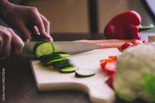 Close up of girl hands while cutting cucumber.