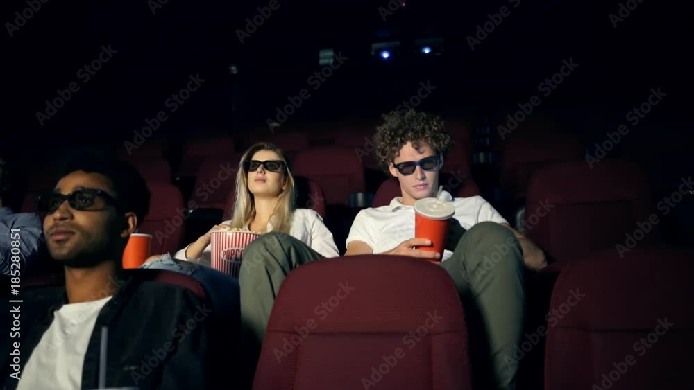 Young modern couples in 3d glasses watching film and eating popcorn in cinema Young modern couples in 3d glasses watching film and eating popcorn in cinema