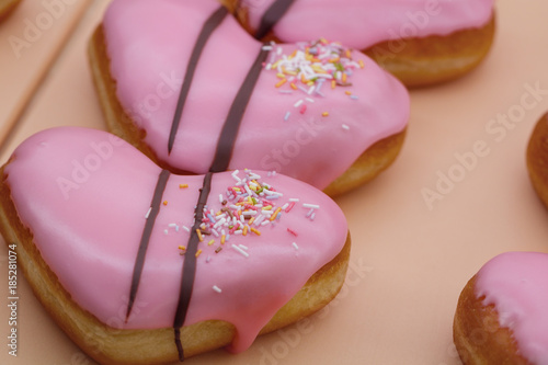 Donuts in the shape of heart with the pink glaze. The gift for Valentine day.