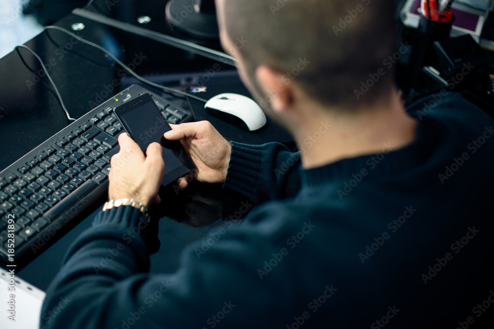 Rear view of young businessman using mobile phone in office Rear view of young businessman using mobile phone in office