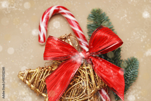 Holiday background image of peppermint candy sticks with Red Bow and golden Decorative Star and Fir Branches on background. Christmas Background.