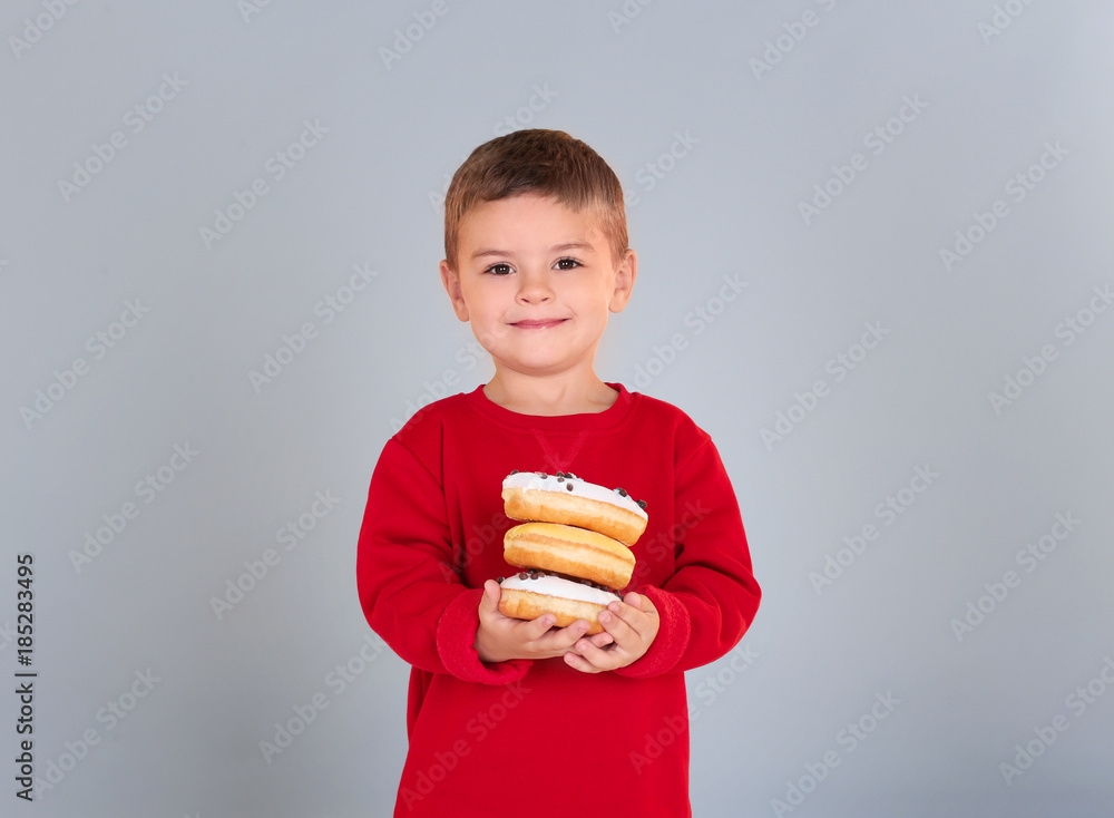 Little boy with sweet donuts on grey background Little boy with sweet donuts on grey background