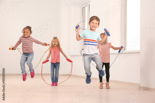 Cute children skipping rope in light room