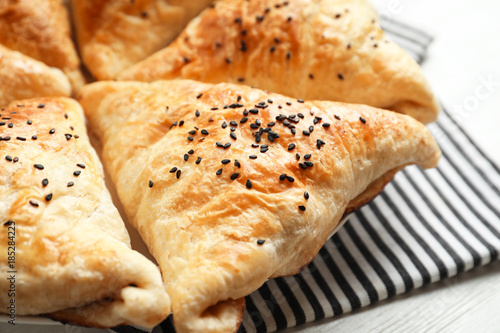 Delicious baked samosas with sesame seeds on table, closeup
