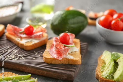Delicious sandwich with salami and cherry tomato on wooden board