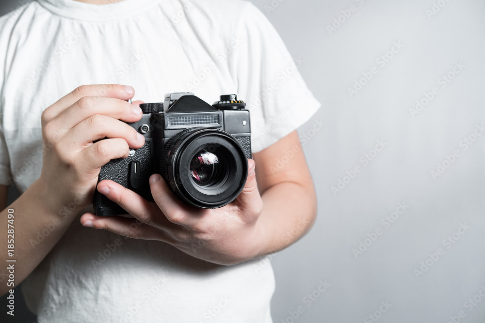old SLR film camera in the hands of a child in a white t-shirt old SLR film camera in the hands of a child in a white t-shirt