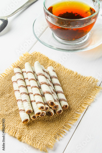 Striped wafer rolls, delicious chocolate snack on white wooden table.
