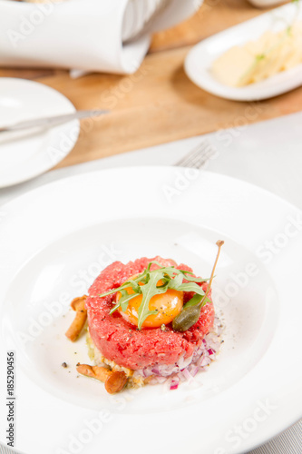 Steak tartare served in a restaurant with egg yolk, onions, caper, mushroom and rocket salad