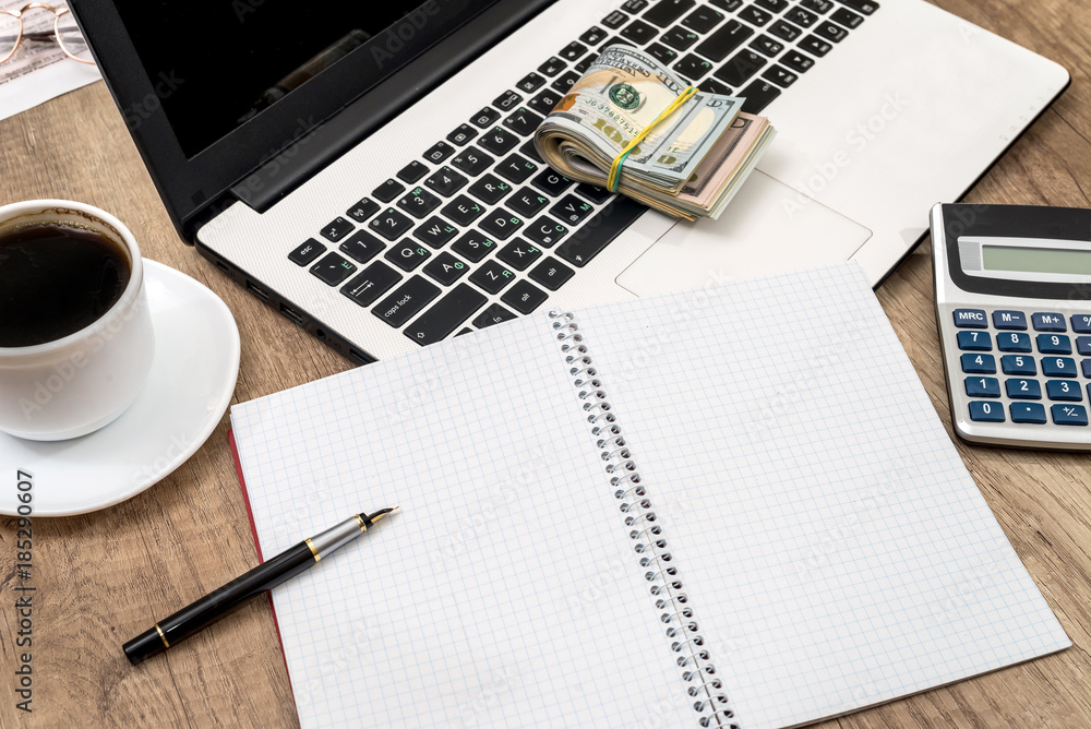 business concept - laptop with notepad, cup of coffee and dollar business concept - laptop with notepad, cup of coffee and dollar