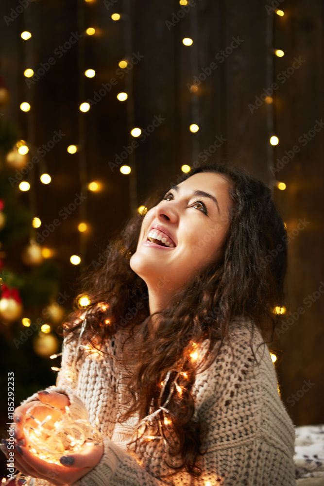 girl with handful of christmas lights, dressed in white sweater, dark wooden background, winter holiday concept girl with handful of christmas lights, dressed in white sweater, dark wooden background, winter holiday concept
