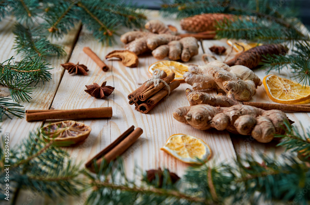 Cinnamon sticks with anise stars, ginger, dried oranges, apples on the wooden background with Christmas tree branches. Traditional spices for mulled wine, Christmas bakery. New Year composition. Cinnamon sticks with anise stars, ginger, dried oranges, apples on the wooden background with Christmas tree branches. Traditional spices for mulled wine, Christmas bakery. New Year composition.