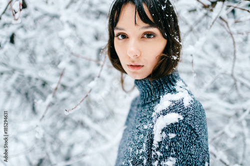 Closeup sensual soft focus portrait of young teenager girl. Emotional amazing beautiful big dark eyes of brunette female looking at camera outdoor in snowy winner forest. Tender, innocent child face.