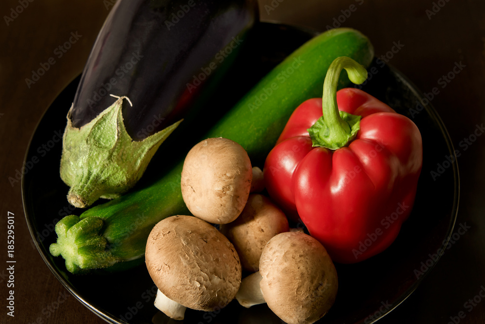 Studio shot of an arrangement of mushrooms, paprika, aubergine and zucchini in a black bowl Studio shot of an arrangement of mushrooms, paprika, aubergine and zucchini in a black bowl