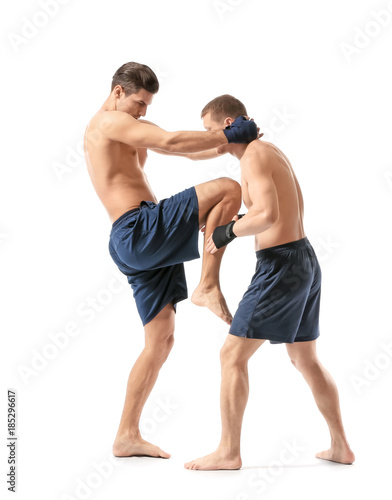 Attractive young kickboxers fighting on white background