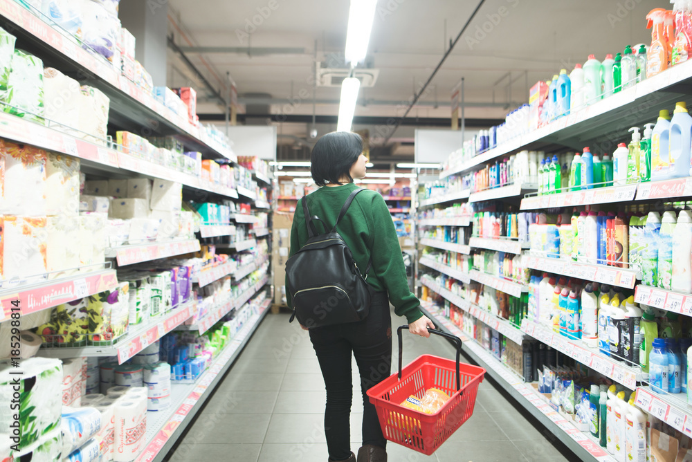 A young girl walks through the supermarket and makes a purchase. Backpacker's girlfriend who goes shopping and buys goods.