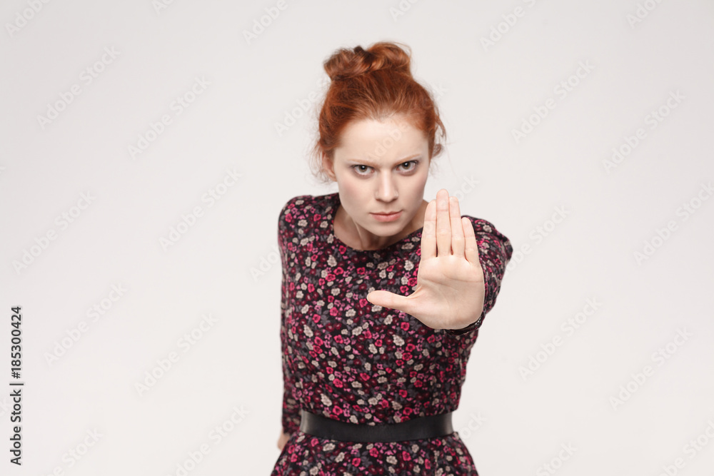 Redhead woman with bad attitude making stop gesture with her palm outward, saying no, expressing denial or restriction. Redhead woman with bad attitude making stop gesture with her palm outward, saying no, expressing denial or restriction.