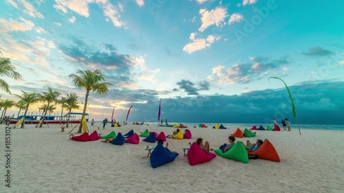 Timelspae People lie on a white beach on pillows and meet the sunset on the island Nusa Lembongan, Bali, Indonesia photo