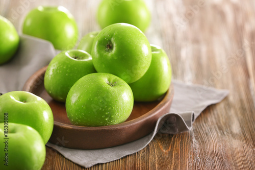 Plate with fresh green apples on wooden background