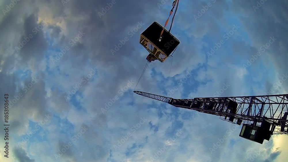 Bottom view of crane lifting man basket, dangerous occupation, industrial Bottom view of crane lifting man basket, dangerous occupation, industrial