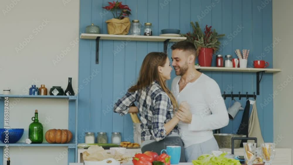 Slowmotion of Cheerful and attractive young couple in love dancing together latin dance in the kitchen at home on holidays Slowmotion of Cheerful and attractive young couple in love dancing together latin dance in the kitchen at home on holidays