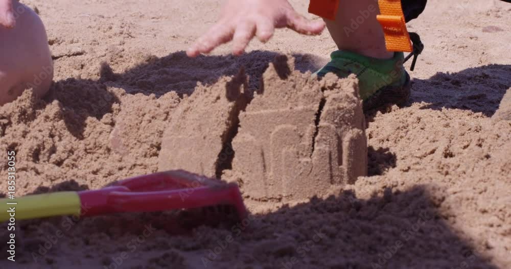 Toddler destroys sand castle on beach - rack focus - bully Toddler destroys sand castle on beach - rack focus - bully