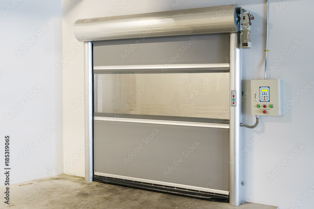 Obraz premium Roller shutter door and concrete floor inside factory building for industrial background.