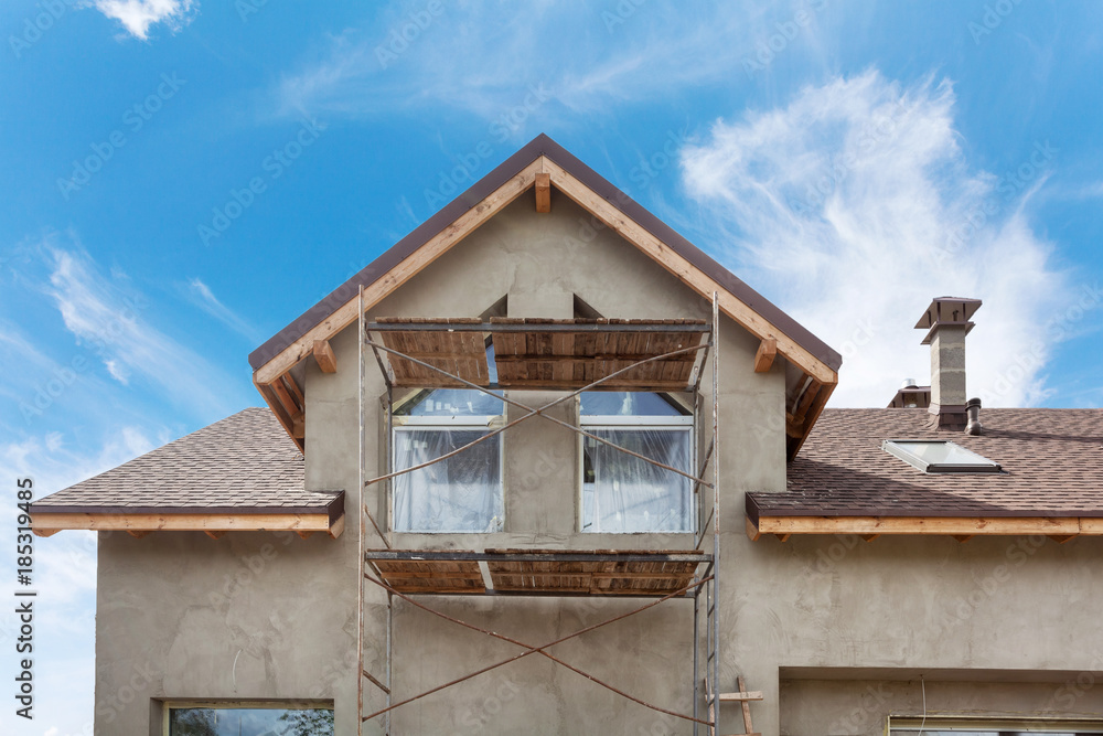 Exterior view of new house under construction and painting. External plaster of the walls of a two-story house Exterior view of new house under construction and painting. External plaster of the walls of a two-story house