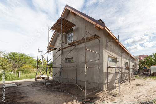Exterior view of new house under construction and painting. Scaffolding for exterior plastering at home side view