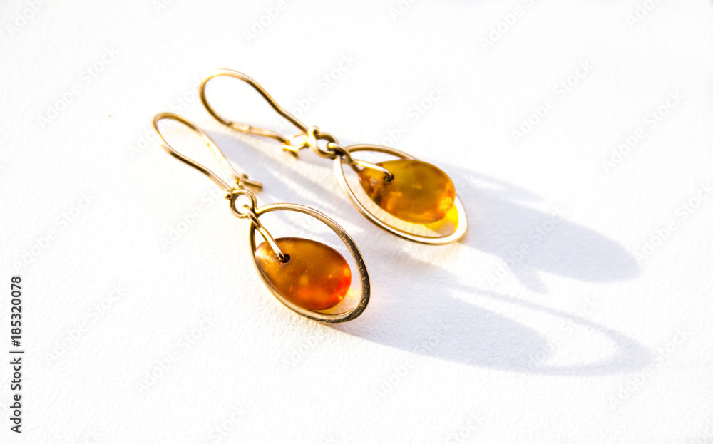Gold earrings with amber on the light background
