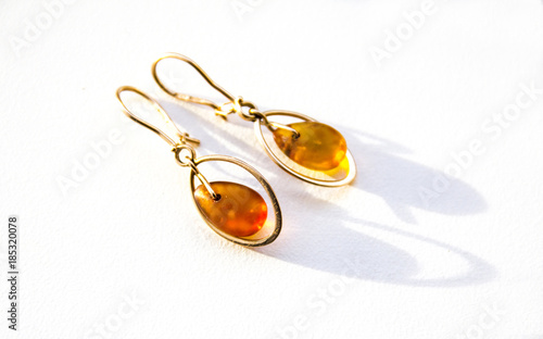 Obraz na płótnie Gold earrings with amber on the light background w salonie