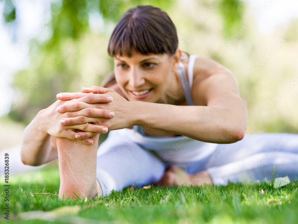Fototapeta premium Young woman practicing yoga in the park