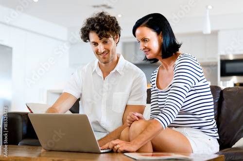 Happy modern couple working on laptop at home