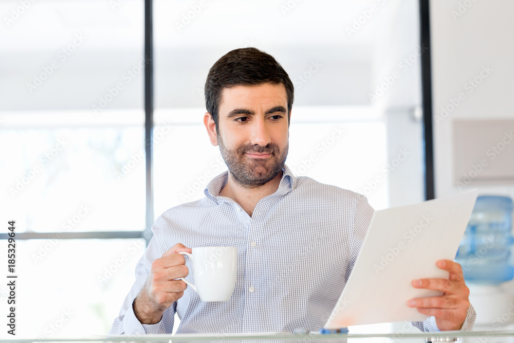 Handsome young man holding paper in office