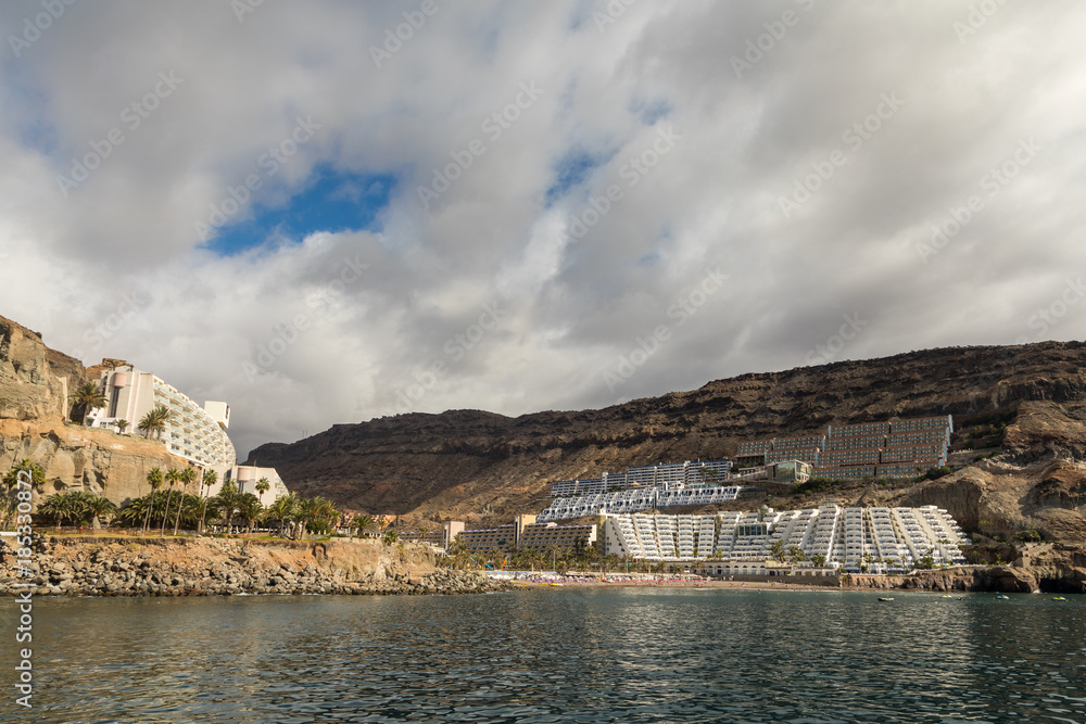 Taurito, Gran Canaria. Beach and hotels seen from the sea, cloudy sky