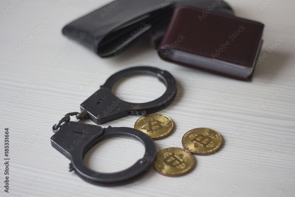 Golden bitcoins, handcuffs and the purse on the wooden table Golden bitcoins, handcuffs and the purse on the wooden table